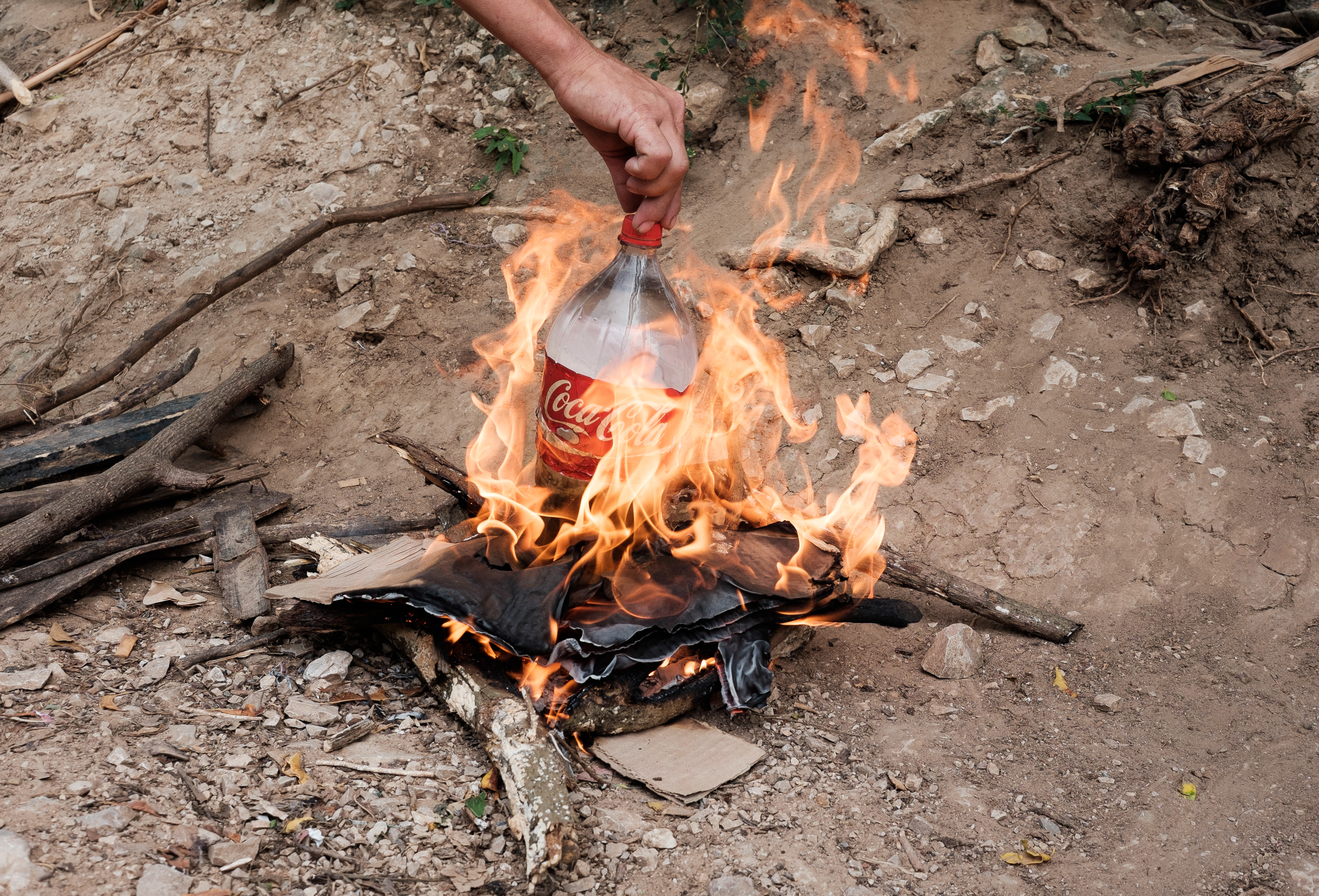 Outside the migrant shelter, a Central American migrant boils water in a Coke bottle for his morning coffee. He carefully adjusts the bottle lid to prevent the water from boiling over or the plastic from burning. Bringing few objects with them on their journey, migrants rely on creative uses of found and recycled items in order to fulfill basic needs.