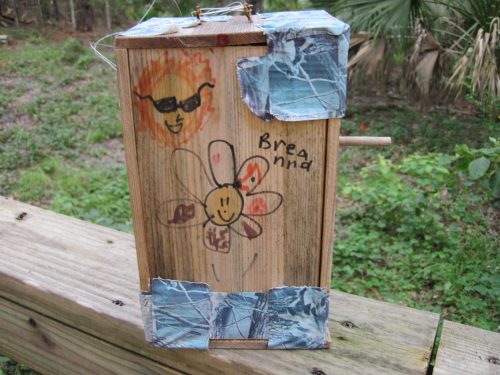 Oftentimes birdhouses bear quotes, signatures, or photographs. Camo tape, along with a child’s hand-drawn images, decorate this homemade birdhouse.