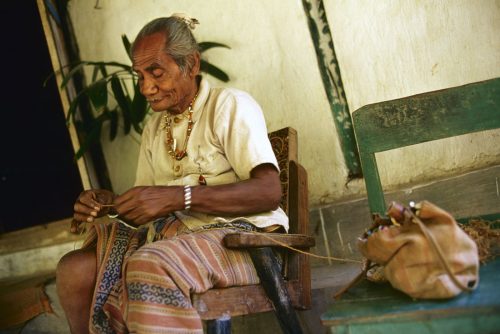 King Ama Nune Benu of Boti sits on his porch, making a bag from fibers grown around him in the forests of West Timor, Indonesia.