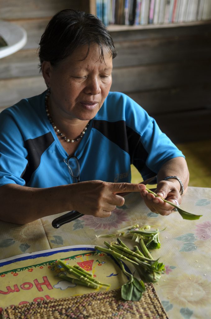 A woman peels vegetables at a table.