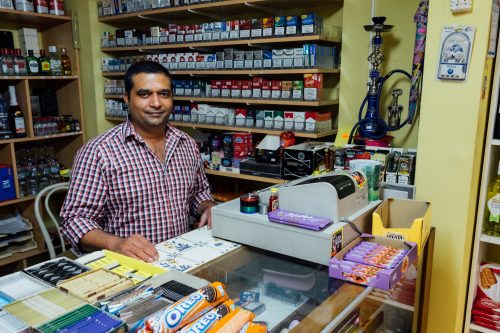 A Pakistani night shop owner in Antwerp’s southern Harmonie neighborhood. While in their shops, many watch their favorite television programs from their native countries or connect with friends and family through social media. Night shop workers often construct and sustain multiple social and economic relations that link their societies of origin with Belgian society. In the process, the boundaries of nation, identity, belonging, and ethnicity become blurred.