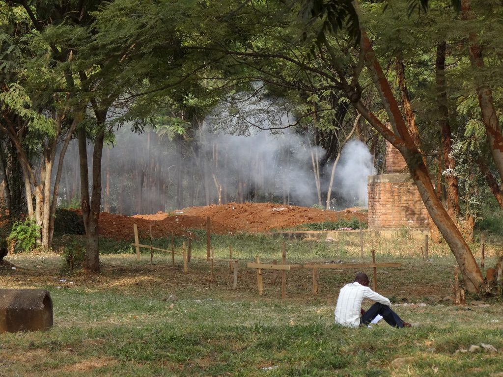 Rwandan Genocide rescuers -In the Rwandan capital of Kigali, a man sits by the graves of genocide victims outside the former École Technique Officielle, a secondary school where some 2,000 people were slaughtered within a few hours.