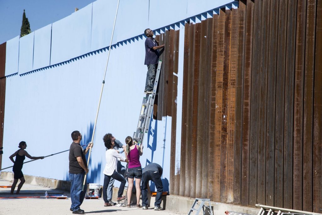 Artists and activists often use the border wall to protest against injustice—in this case by using sky-blue paint to symbolically erase the wall.