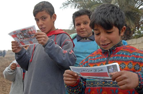 Some modern militaries distribute leaflets, such as the ones these Iraqi boys are reading, in an attempt to convince people to believe certain things or behave in a particular way.