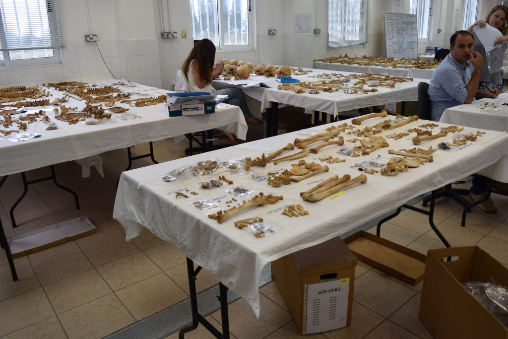 In a lab, scientists study human remains laid out on a table.