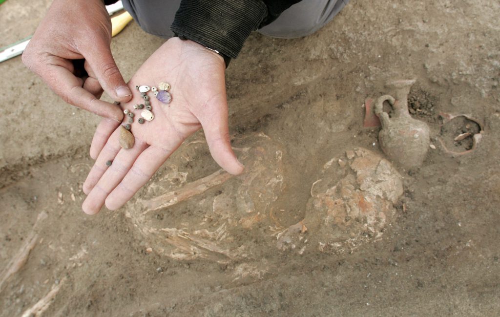 hominin burial - An archaeologist shows necklace beads that were found with human remains in a grave at the site of the ancient Egyptian fortress of Tharo, in the northern Sinai Desert.