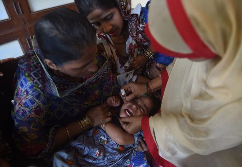 polio eradication pakistan - A health worker in Karachi, Pakistan, delivers polio vaccine drops to a child.