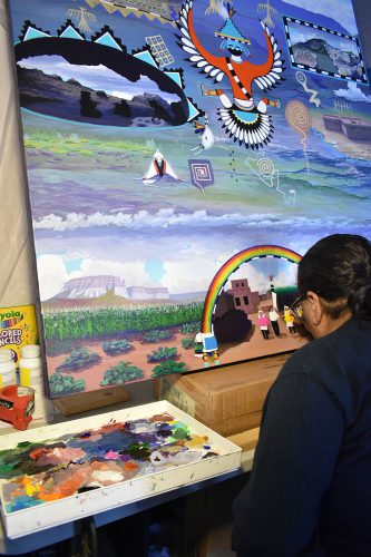 Zuni artist Ronnie Cachini works on his painting in his studio.