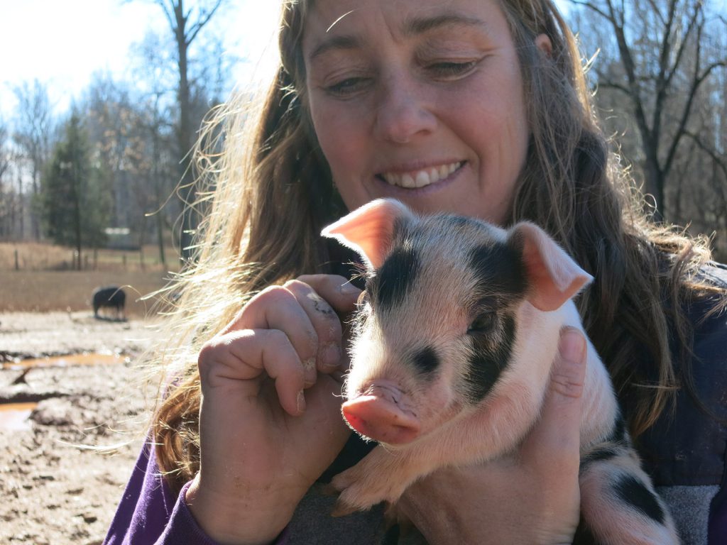Eliza MacLean of Cane Creek Farm cradles a baby pig.