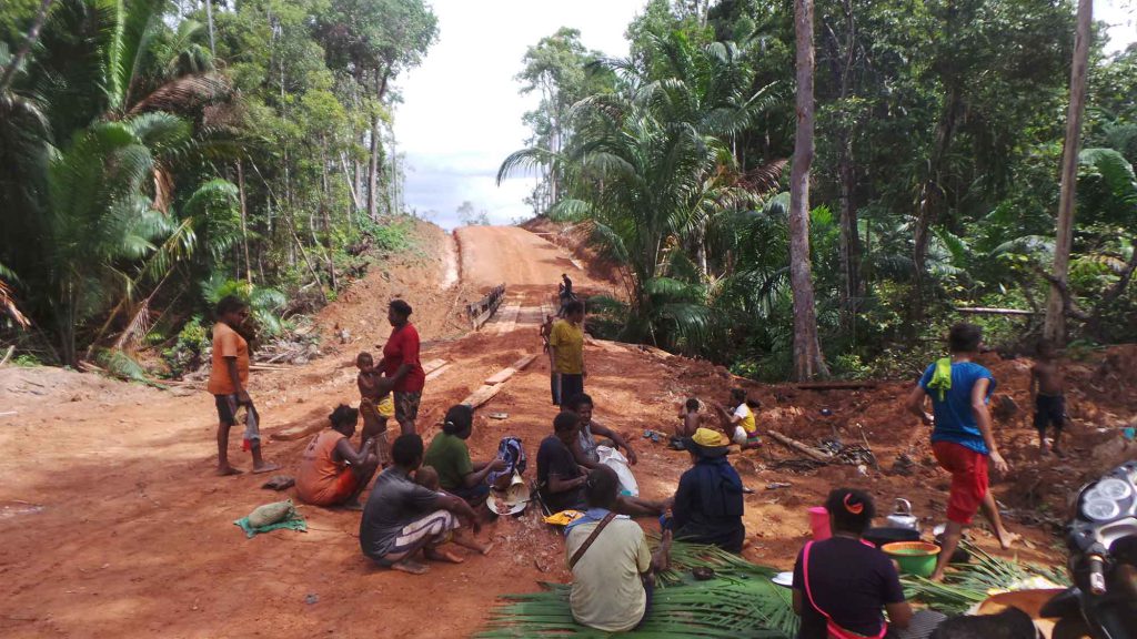 A group of Marind gather near a forested area that has been demarcated as a conservation zone.