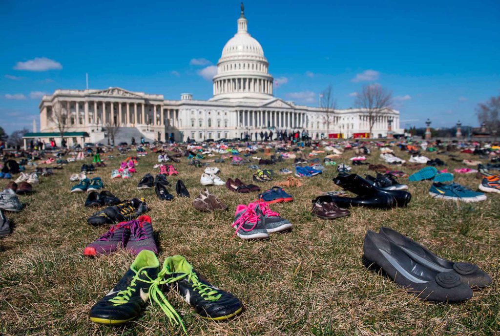 gun research ban - Shoes representing the estimated 7,000 U.S. children who were killed by gun violence since the 2012 Sandy Hook Elementary School shooting cover the Capitol lawn in 2018.