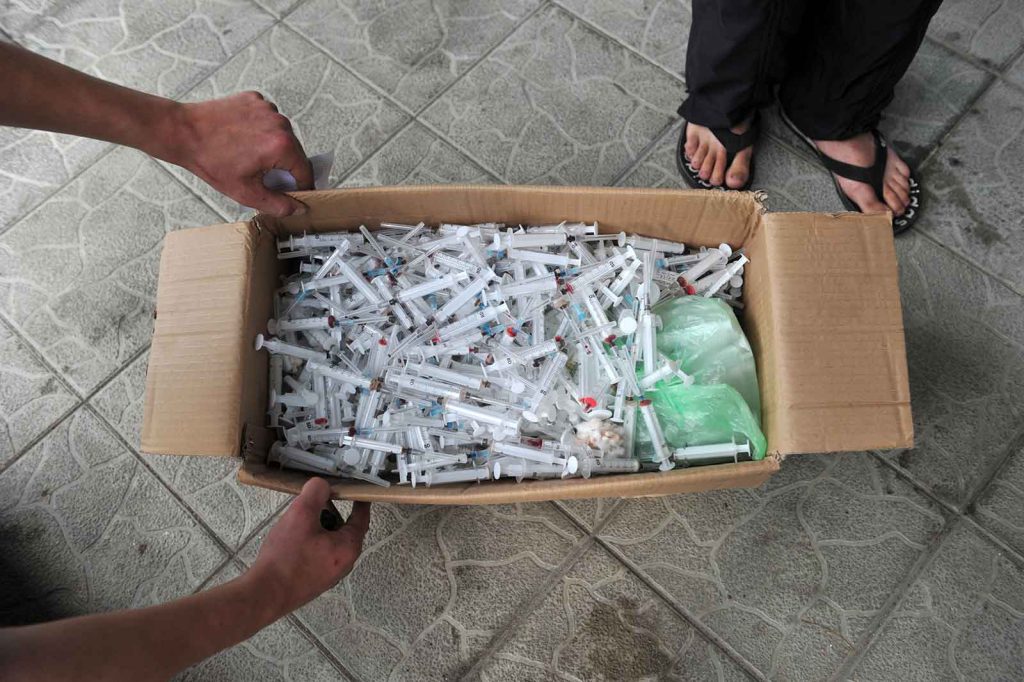 Drug Use - A social worker collects used syringes at a needle exchange site in the Ukraine. As the country has expanded its free sterile syringe program, HIV infections via needles have dropped.