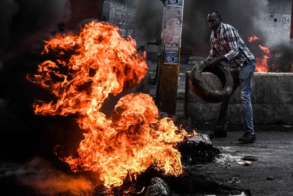 A man burns tires to block off a street in protest against worsening fuel shortages, closed gas stations, and blackouts.