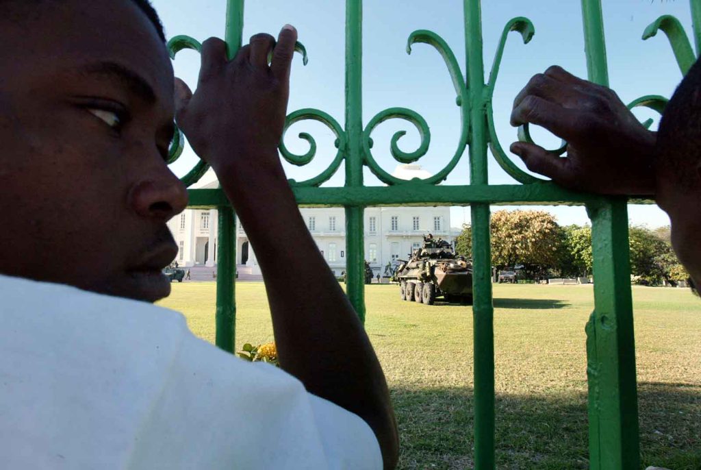 A U.S. Marine light armored vehicle parks at the Haitian presidential palace in the wake of the 2004 coup that ousted then-President Jean-Bertrand Aristide and led to the murder and sexual assault of thousands of Haitians.