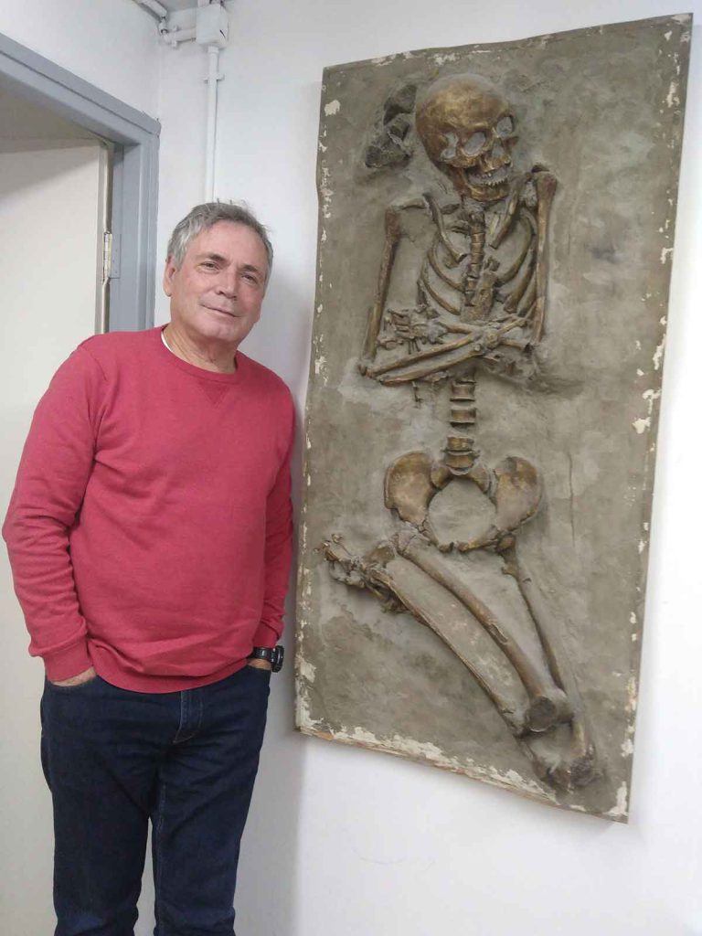 Anthropologist Israel Hershkovitz stands by a cast of human remains in his office.