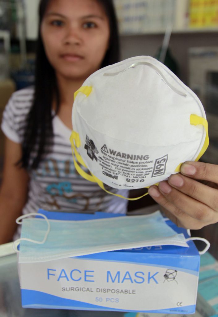 A store employee in Manila, the Philippines, holds an N95 respirator over a box of surgical masks.
