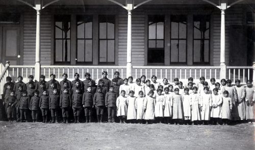 Many Native American boarding schools imposed a militaristic system featuring regimented schedules, adherence to order, and technical training. Children were dressed in crisp uniforms and lined up like soldiers for this photo at the Cantonment Boarding School in Oklahoma, which was previously a U.S. Army barracks.