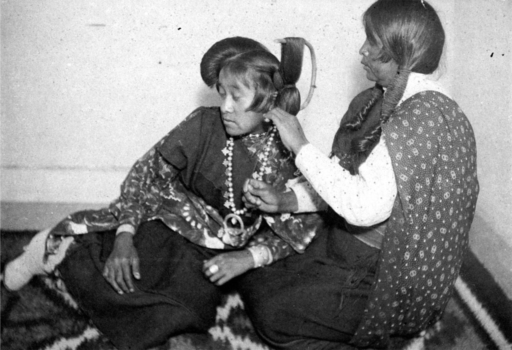 While teaching on the Hopi Reservation in Arizona, Bratley likely posed this image of his student Ruth Honavi having her hair made up in the butterfly style. Hopi culture likens women to gentle, life-giving butterflies, and this tradition continues today for girls participating in ceremonies. Bratley once wrote that long hair was “a part of [Indigenous peoples’] very being and religion,” yet he encouraged cutting boys’ hair.