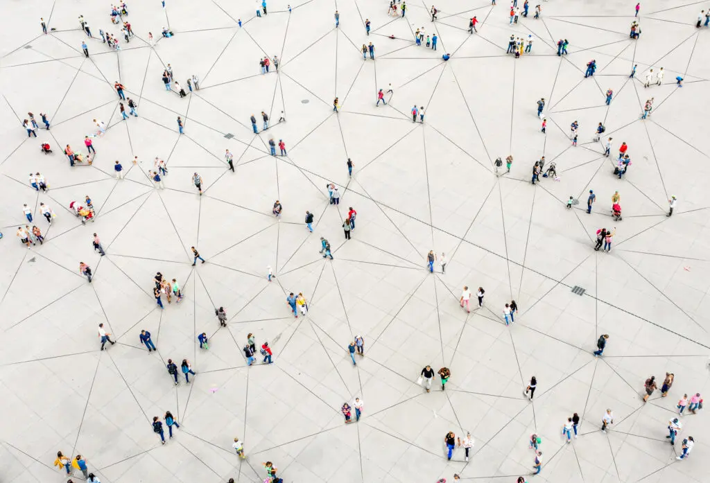 From aerial view, various individual and clusters of people in a crowd are connected by thin black lines against a beige ground.