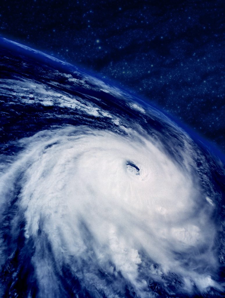 An enormous, swirling white cloud rapidly travels over an ocean.