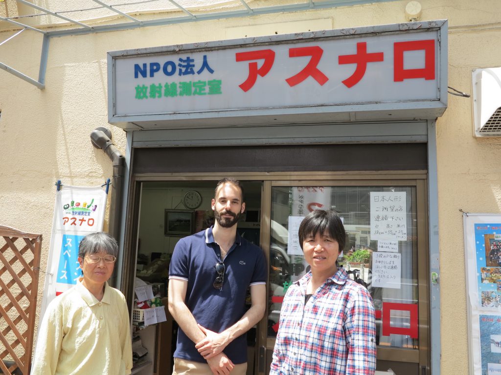 The author (center) stands with two community members in front of a citizen science center.