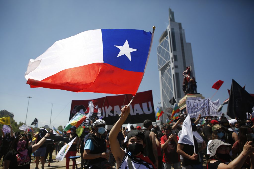 Chile democracy dignity - A protestor in 2020 in Santiago waves the Chilean flag.