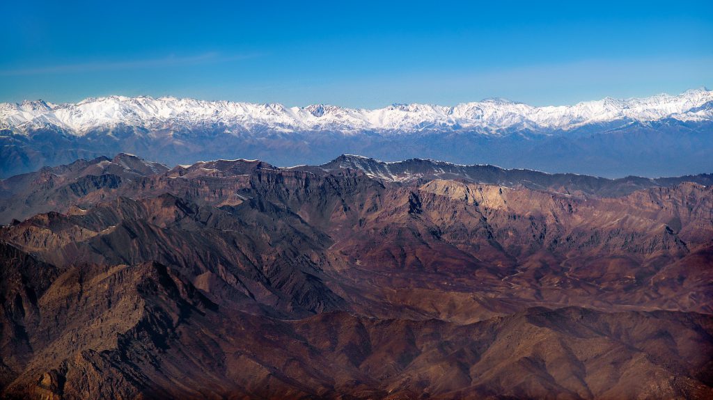 A massive, impenetrable mountain range stands against an even more daunting mountain range with peaks covered in snow.