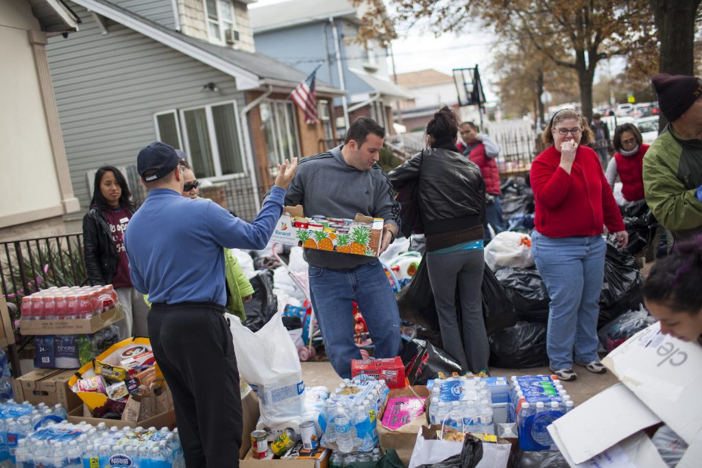 A group of people stand amid cases of bottled water and drinks.