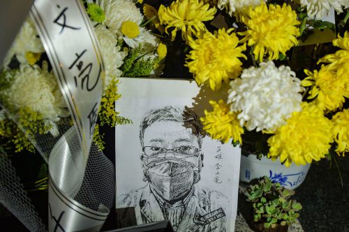 A black-and-white sketch of a man with short hair, glasses, and a mask rests in front of bouquets of yellow and white flowers and a white ribbon with Chinese characters on it.