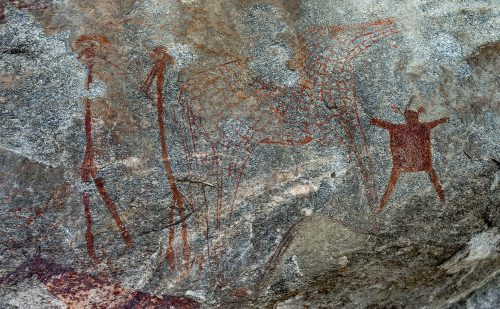 An image features a group of figures drawn in reddish-brown paint on a rock face in what is today Tanzania.