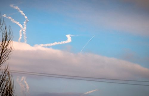 Anti-aircraft missiles leave white contrails in a blue sky above Kyiv, Ukraine.