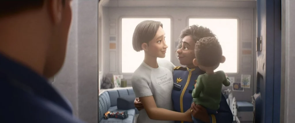 An animated film still features two women giving each other side hugs and looking into each other’s eyes. The one on the right carries a child in her other arm.