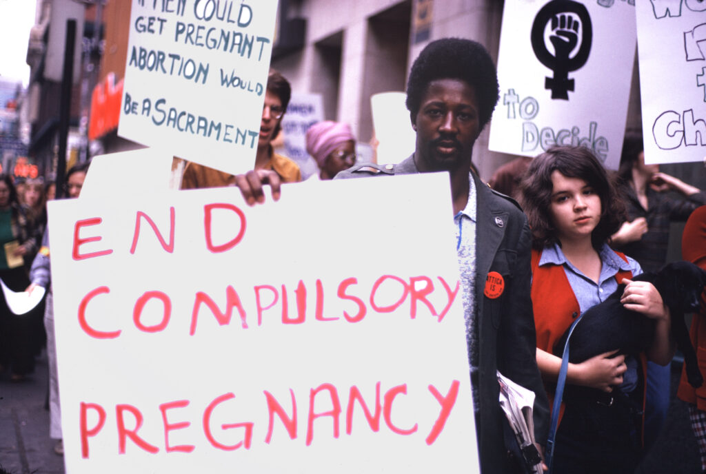 Protestors hold signs that read: “End compulsory pregnancy” and “If men could get pregnant abortion would be a sacrament.”