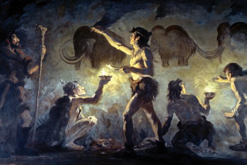 Una ilustración en color muestra a los antiguos humanos pintando mamuts en la pared de una cueva.