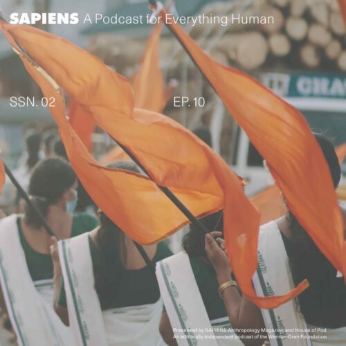 Orange flags are held by women all lined up in a row.