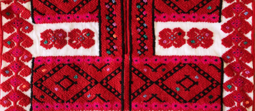 A close-up image features a mostly red, woven piece of cloth with diagonal patterns that incorporate white, black, green, and hot pink accents.