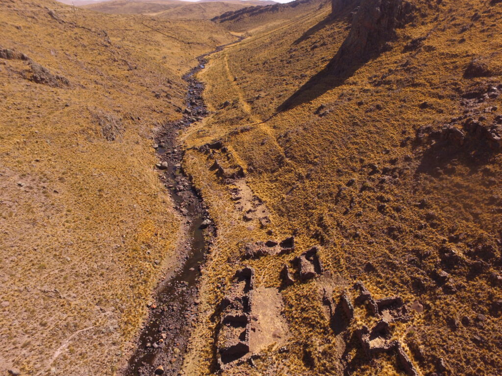An aerial photograph shows a long narrow river cutting through a dirt field, with both sides inclining upward from it.