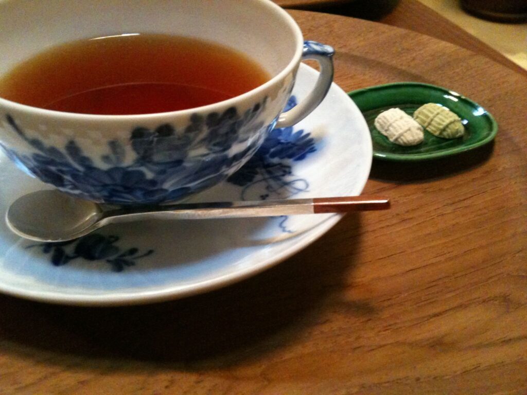 A small cup half filled with brown liquid rests on a saucer on a wooden table.