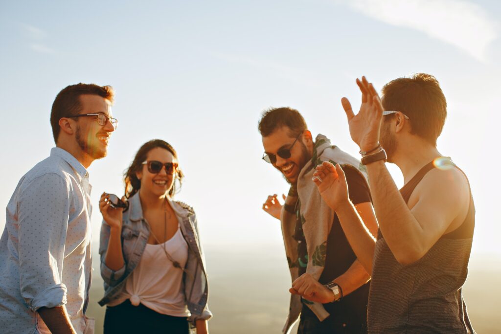 A photograph features four smiling people wearing sunglasses and dancing together.