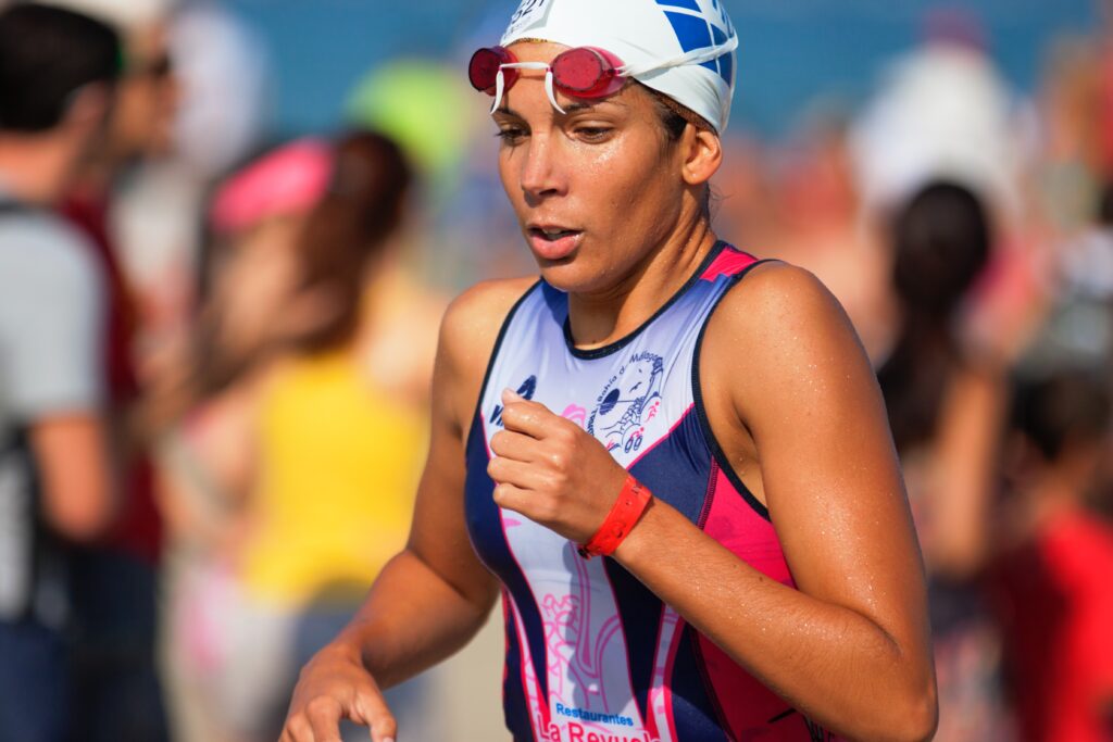 A person runs while wearing a swimsuit and on their head, a swim cap and goggles.