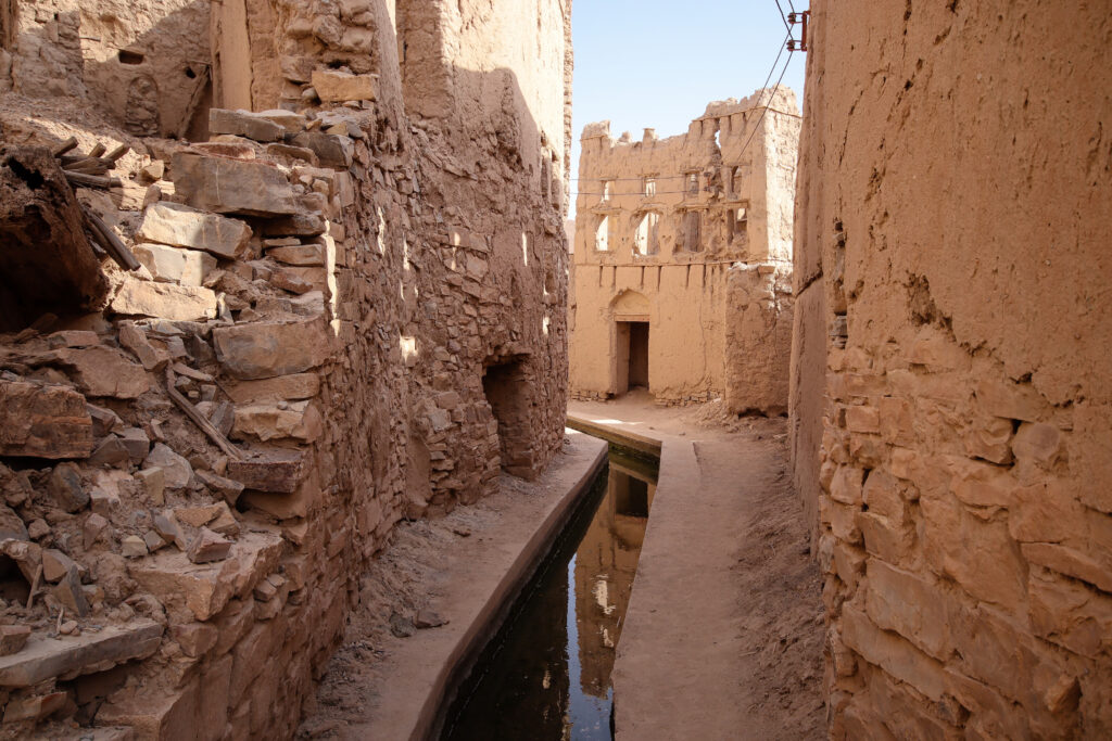 A canal holding water extends from the front to the back of the image lined by tall stone buildings.