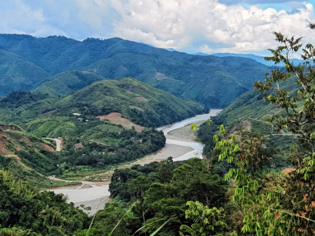 Um rio serpenteia por um vale entre montanhas cobertas por florestas.