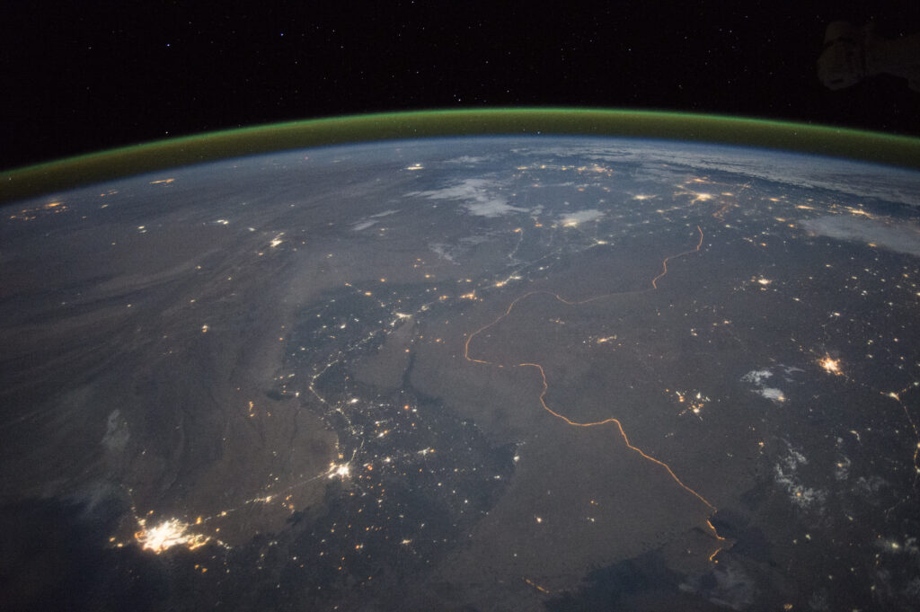 Taken from outer space, a photo features landmasses and blue water under various groups of lights and extensive lines.
