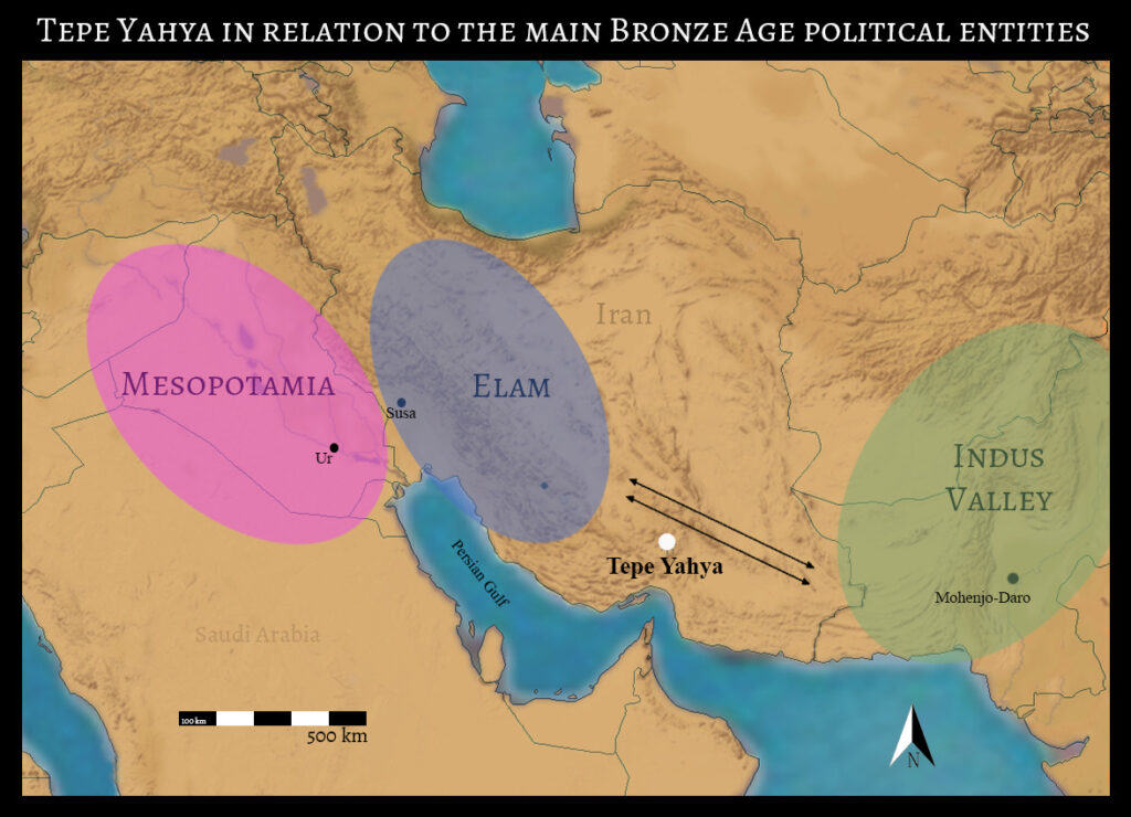 A terrain map of present-day Iran has three circles highlighting land regions around a blue body of water labeled “Persian Gulf.” The text above it reads “Tepe Yahya in relation to the main Bronze Age political entities.” Leftmost is a pink circle with text inside it that reads “Mesopotamia.” To its right is a gray circle with text that reads “Elam.” On the far right is a green circle with text that reads “Indus Valley.” Between the two rightmost circles is a white dot labeled “Tepe Yahya” below two parallel arrows pointing between—and thus associating—the circles.