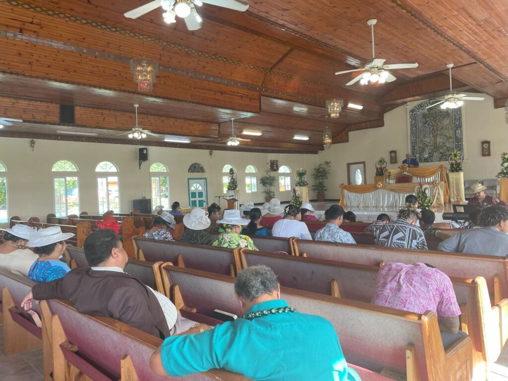 A church service with many people in colorful clothing sitting in pews,