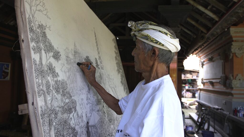 Under an arched ceiling, a person wearing a white headwrap and T-shirt nestles a pencil in the palm of their hand while drawing with charcoal on a large white canvas. The scene they are sketching depicts a building and public square flanked by flowering trees.