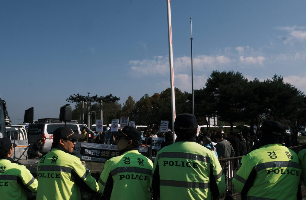 Police in bright yellow jackets stand in front of protestors.