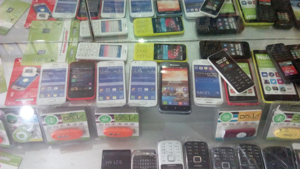 A colorful variety of smartphones and cellular phones sit in a glass display case.