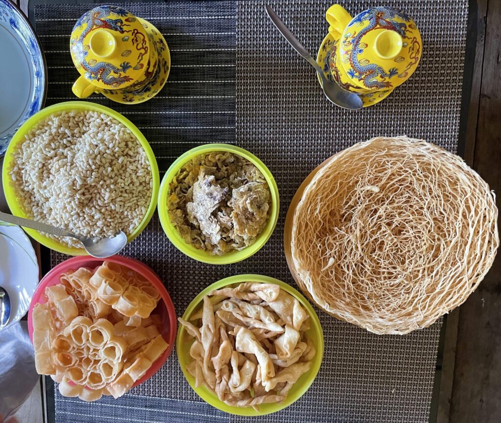 Green and red bowls on a table are filled with rice and other delicacies.