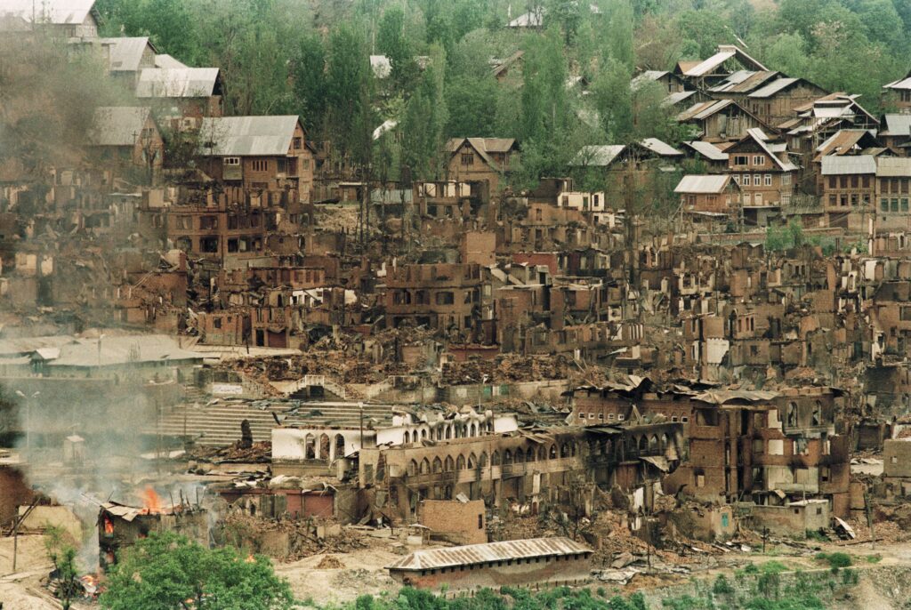 A mosque, shrine, and houses lie in ruins after having been burned.